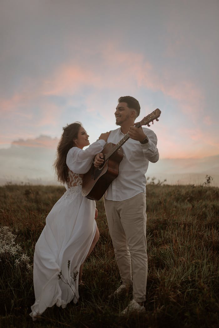 A romantic scene of a couple enjoying music with a guitar at sunset in a scenic meadow.