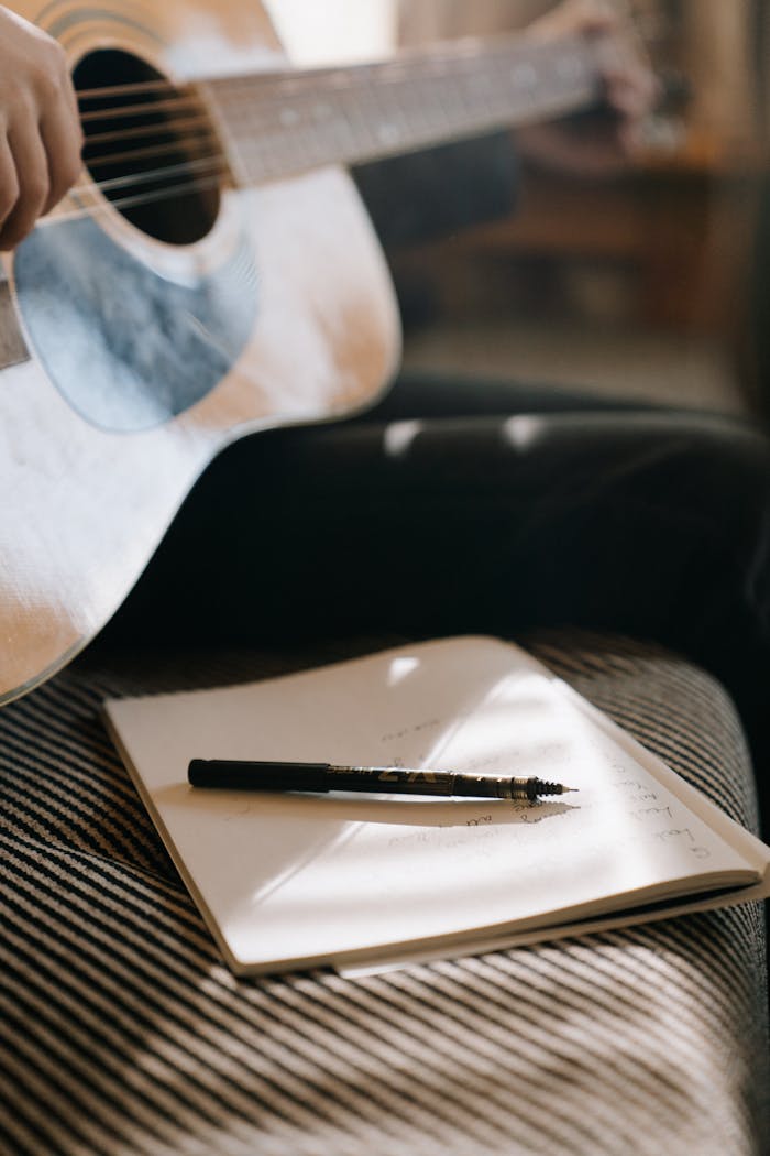 Close-up of an acoustic guitar and notebook, capturing a calm songwriting moment.