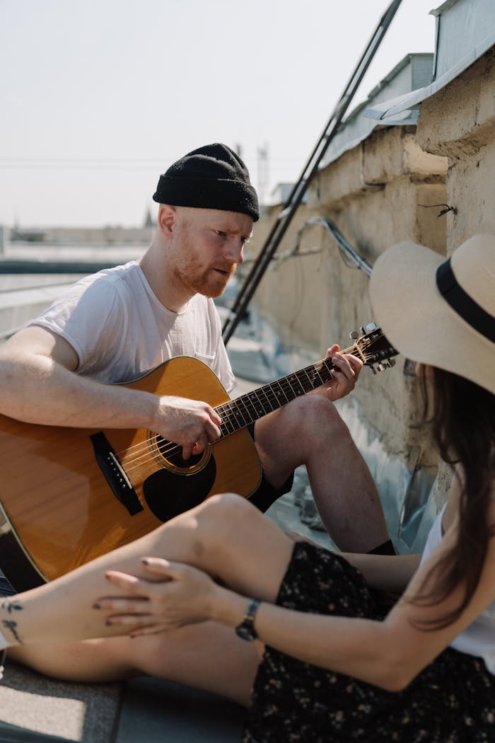 A couple enjoys a romantic guitar serenade on a sunny rooftop, creating a moment of love and leisure.