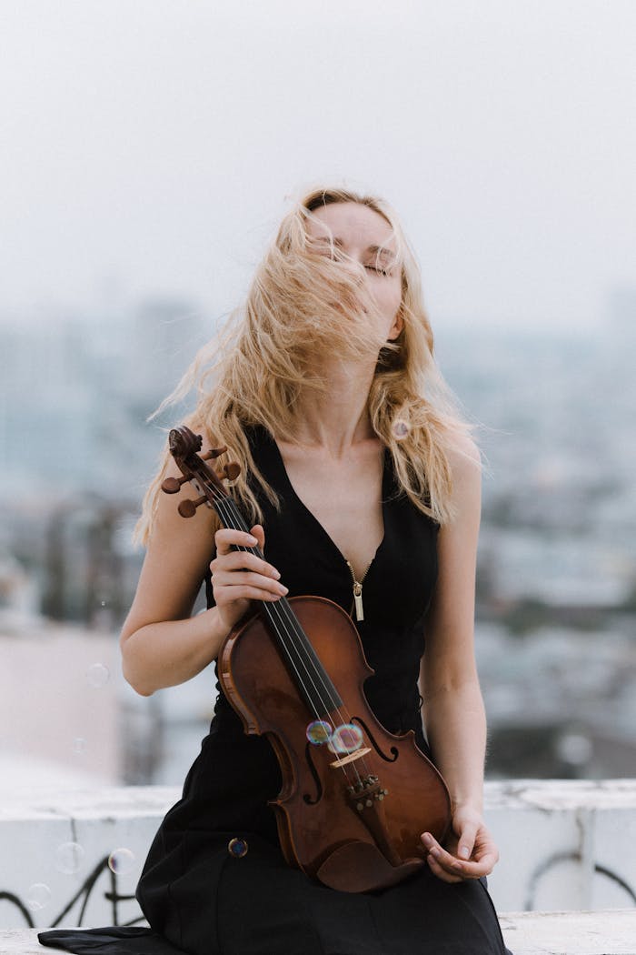 A serene moment captured of a woman with a violin, standing outdoors on a rooftop.