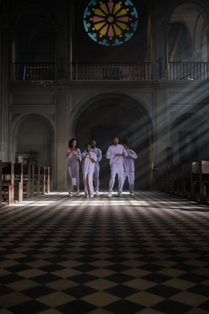 A diverse choir group sings in a historically designed cathedral, flooded with sunbeams.